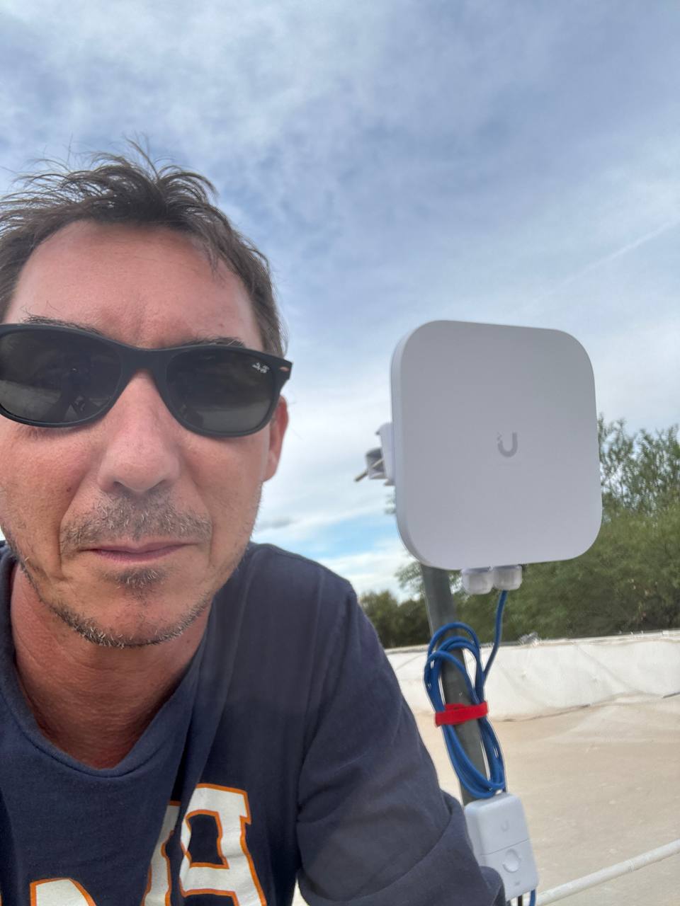 Drew Phillips beside an outdoor Wi-Fi access point during a Tucson installation